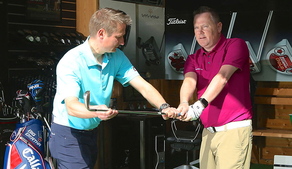 Anders teaching blind golfer with hands on the club