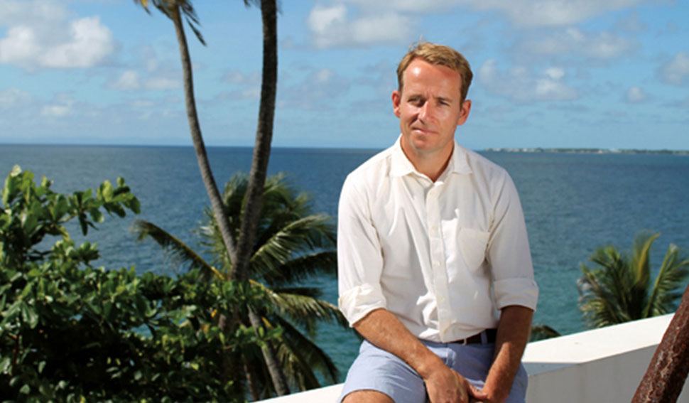 Jonnie Urwin sitting on balcony with the sea in the background